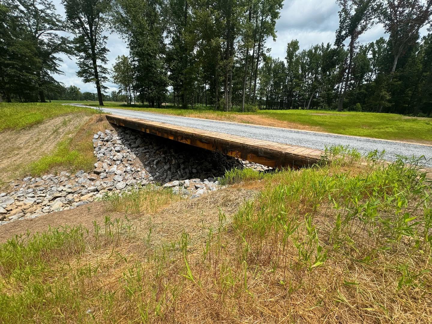 Gravel road crossing a bridge over a rock-lined channel
