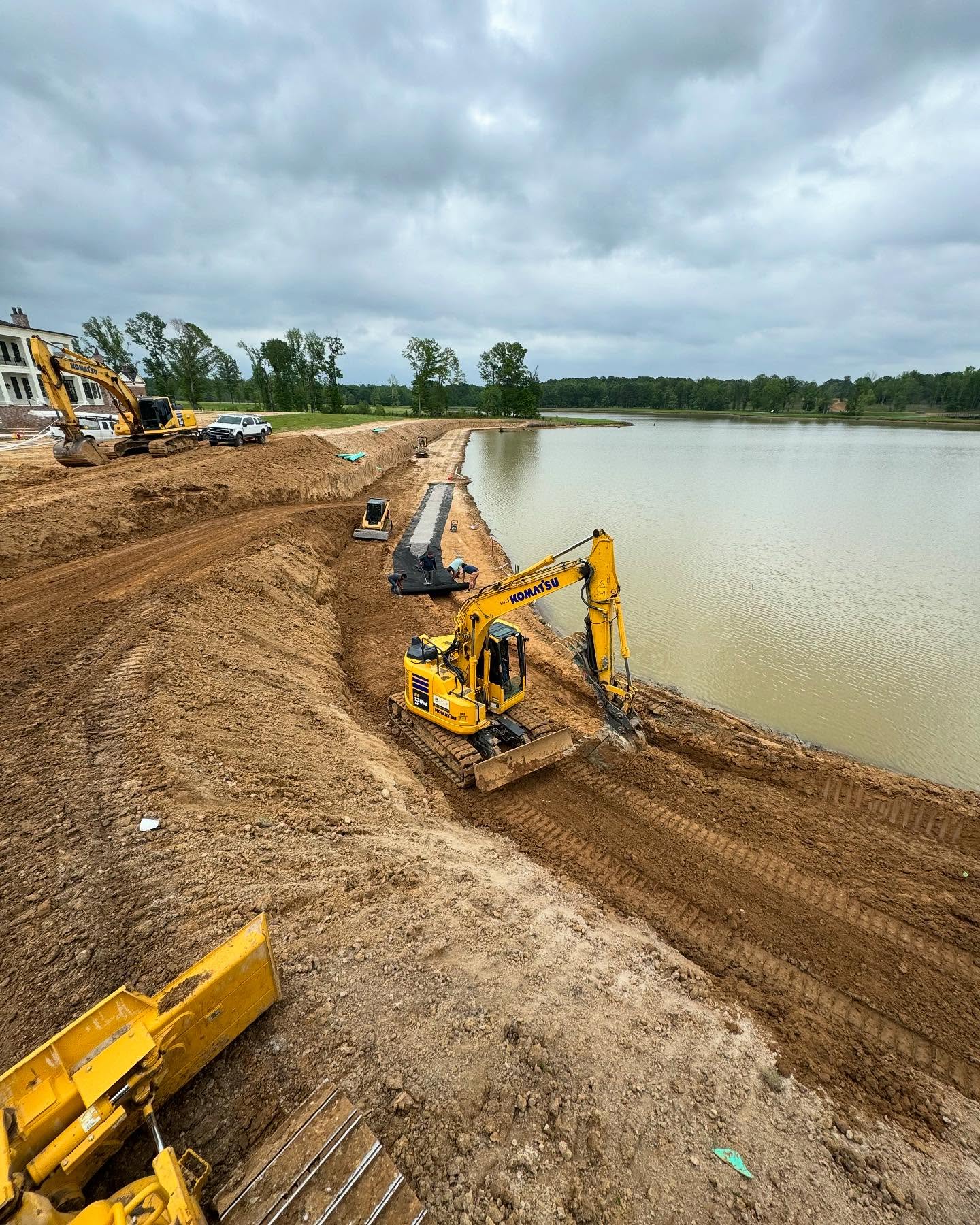 Excavators working along a pond bank