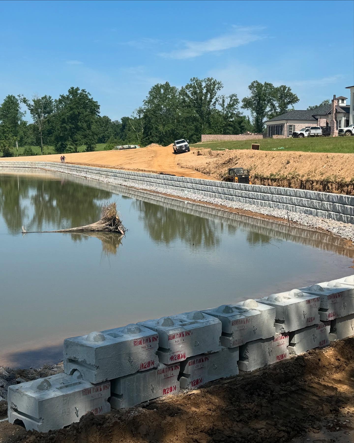 Retaining wall construction along a pond with exposed soil above